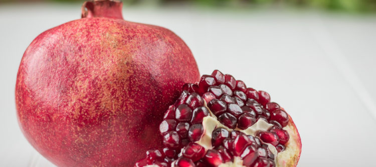 a photo of a ripe pomegranate and seeds on a table