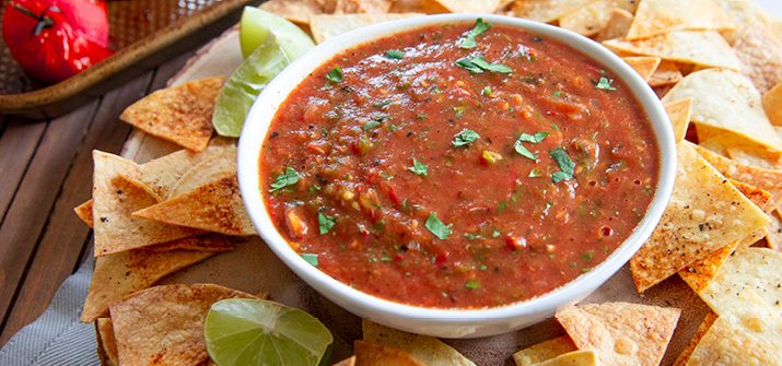 a photo of roasted tomato salsa in a bowl surrounded by chips