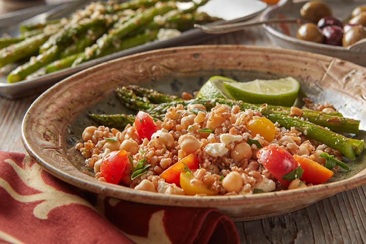 Mediterranean Farro Salad in a dish served with asparagus and lime