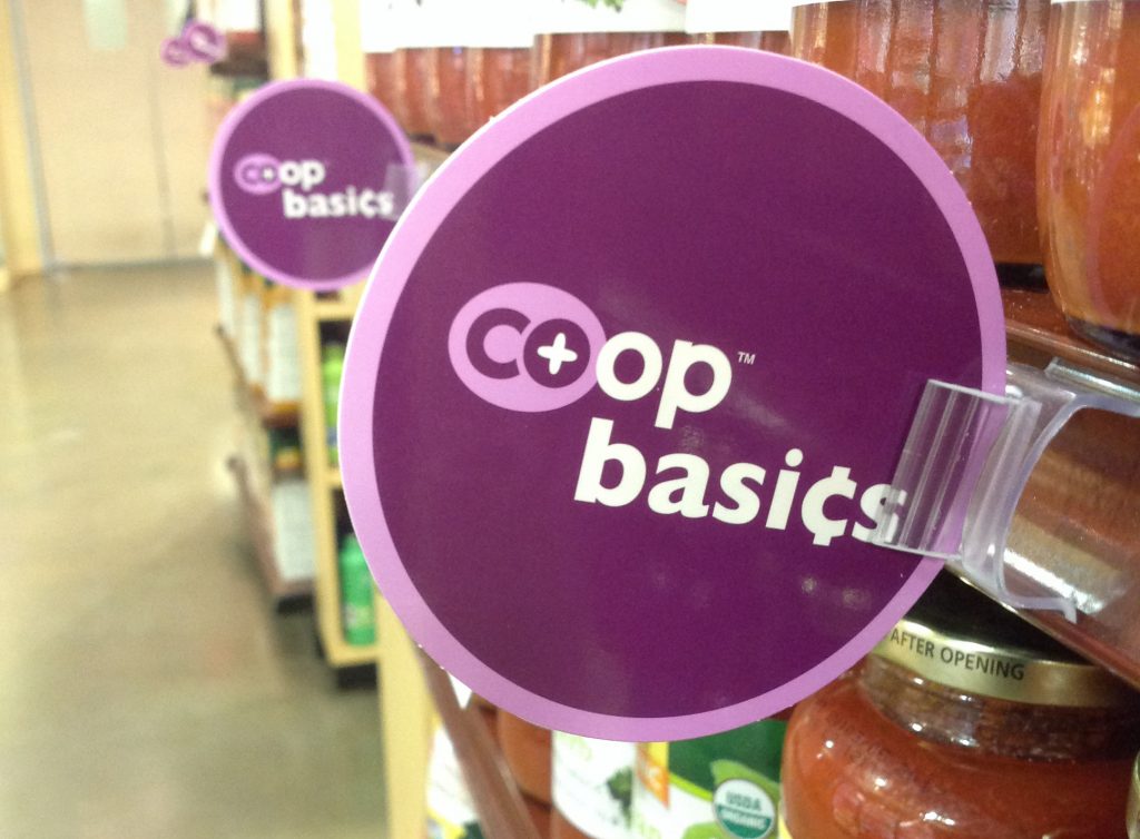 a grocery store aisle with a purcple circle sign sticking out from the shelves